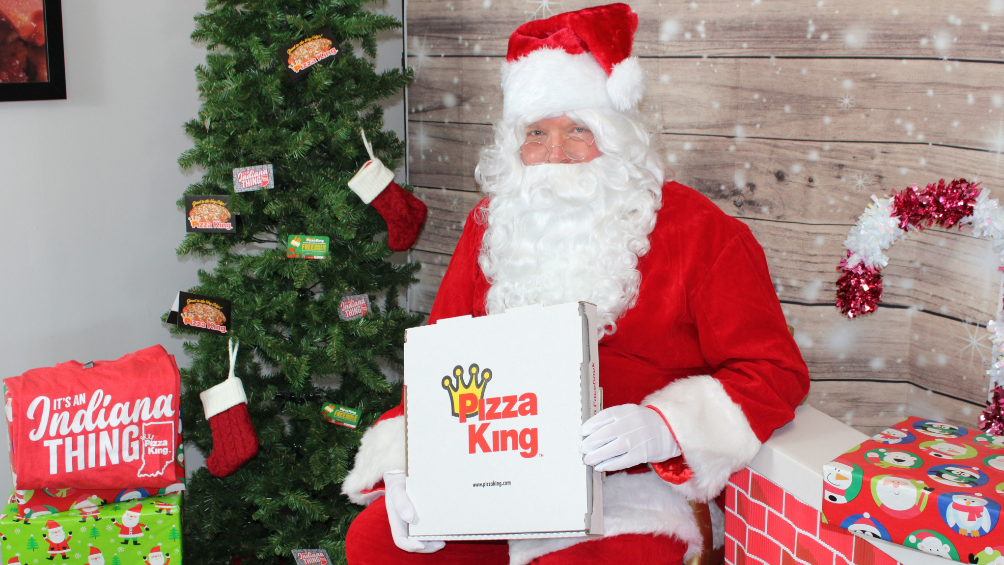 santa holding a pizza box, presents around